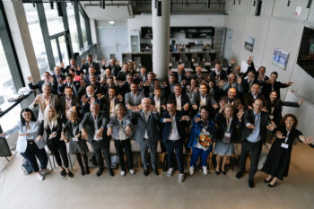 Gesamtes Gruppenfoto, alle heben ihre Hände in die Höhe